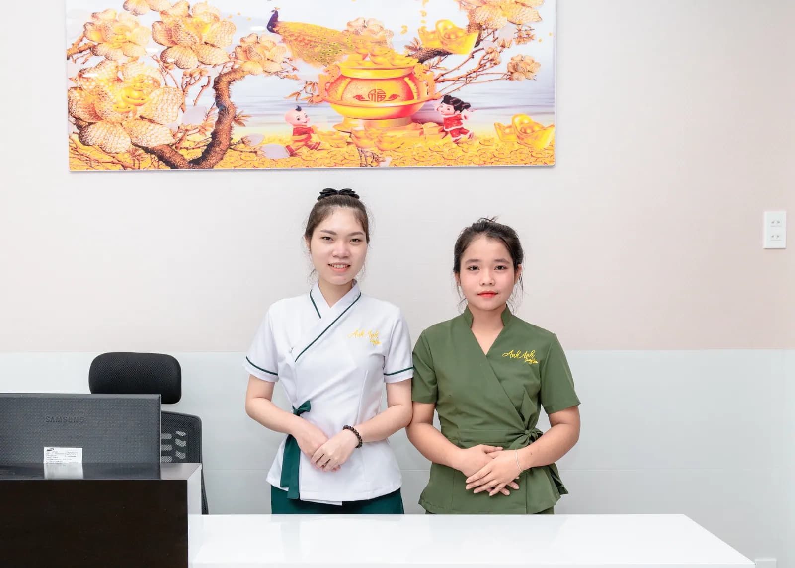 Hai người đứng cạnh nhau phía sau quầy trắng