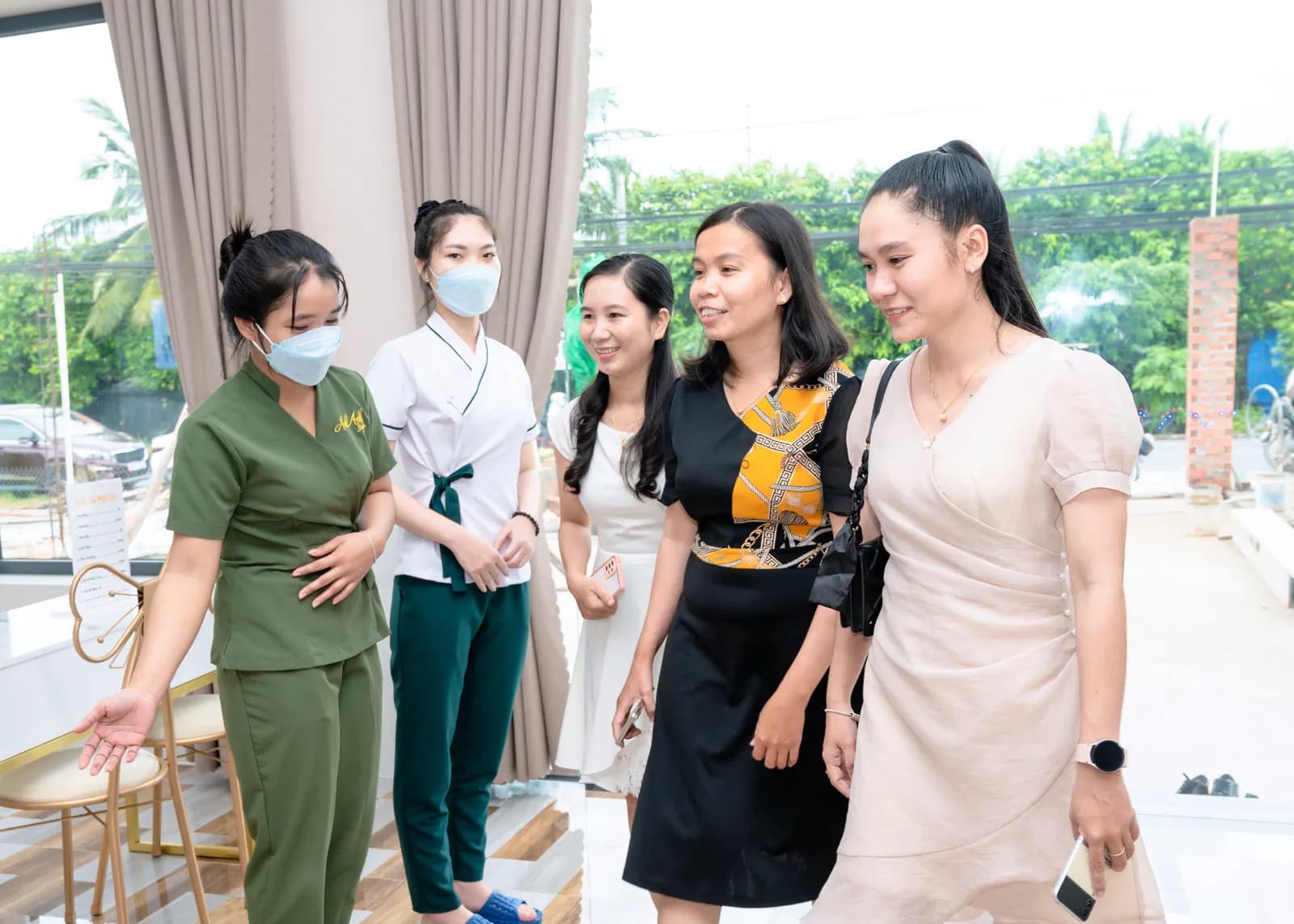 Nhóm người bước vào qua cửa kính bên cạnh rèm sáng