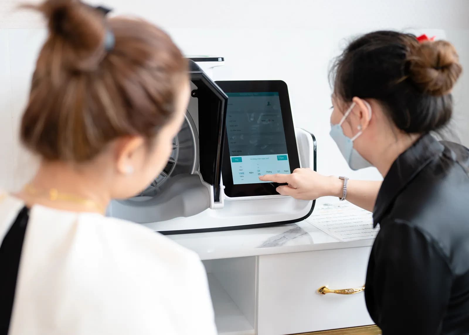 Hai người quan sát màn hình một thiết bị đặt trên bàn