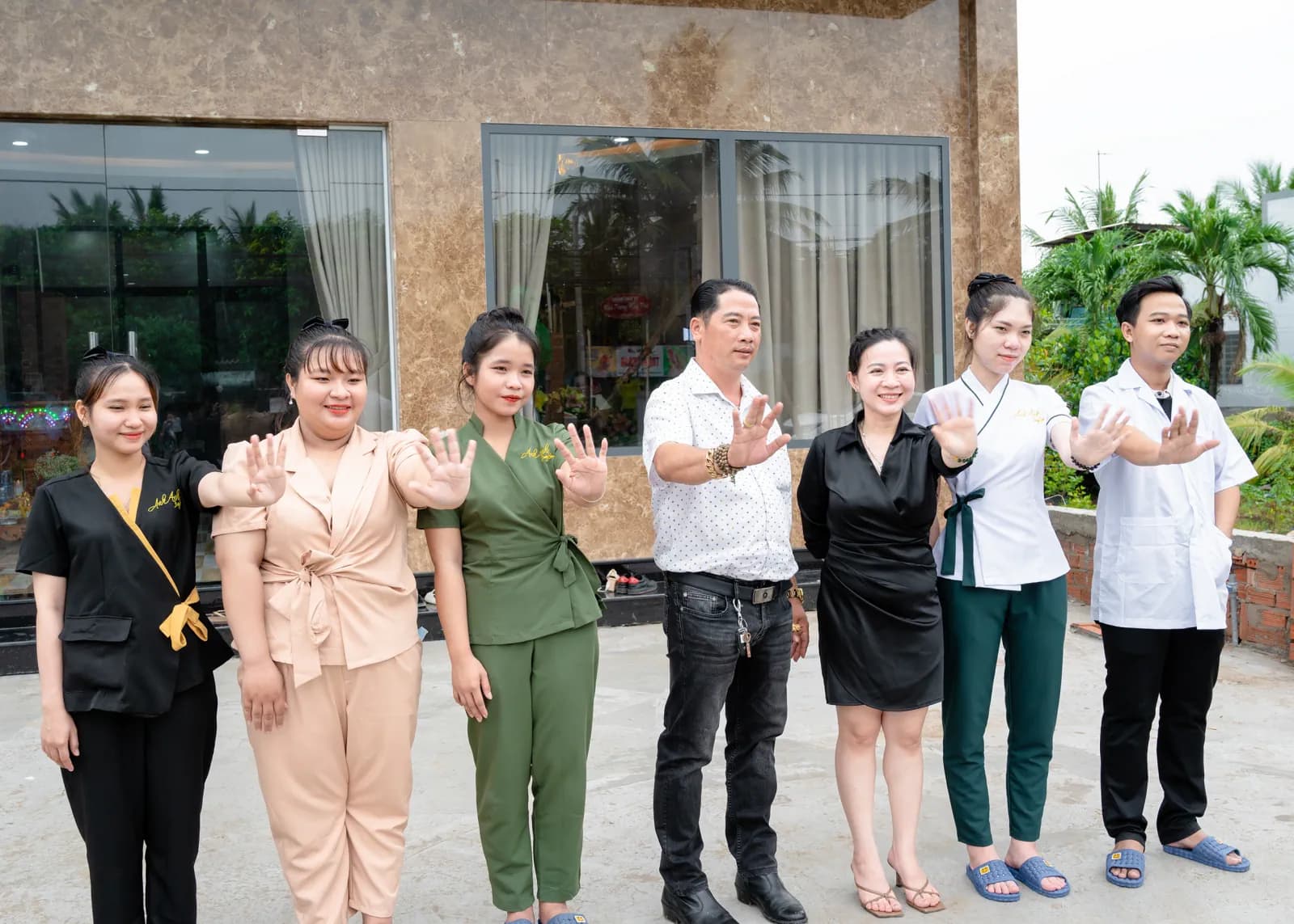Một nhóm người đứng cạnh nhau trước mặt tiền