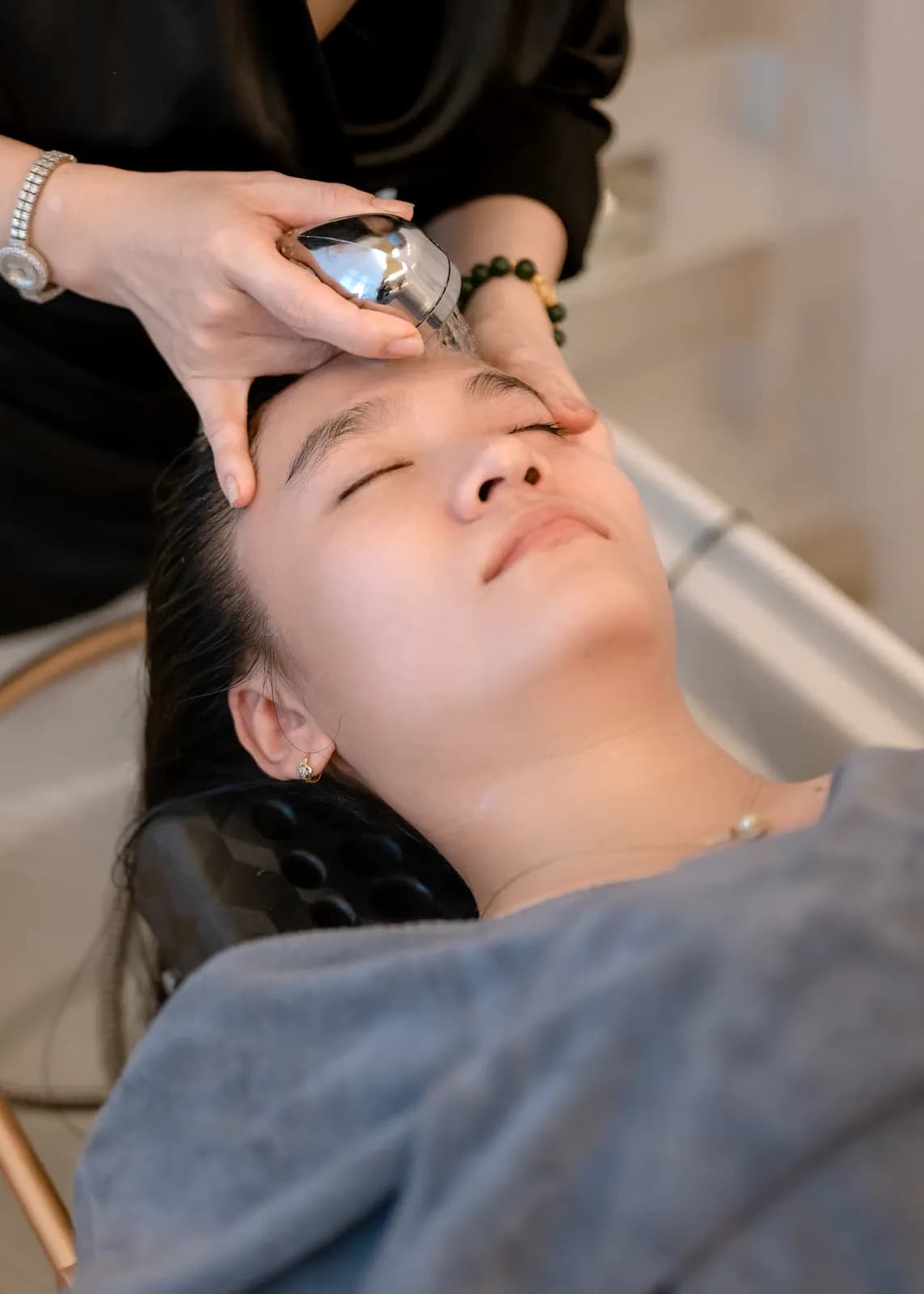 Bàn tay cầm dụng cụ nhỏ phía trên gương mặt người nằm