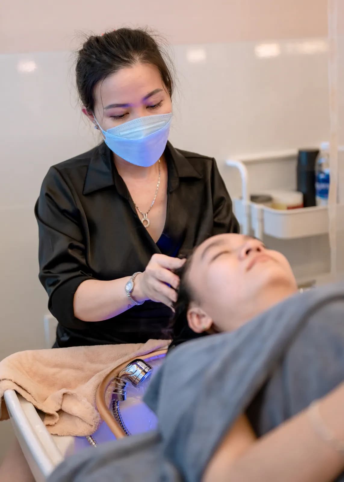 Người mặc áo đen đứng sau người nằm cạnh bồn gội