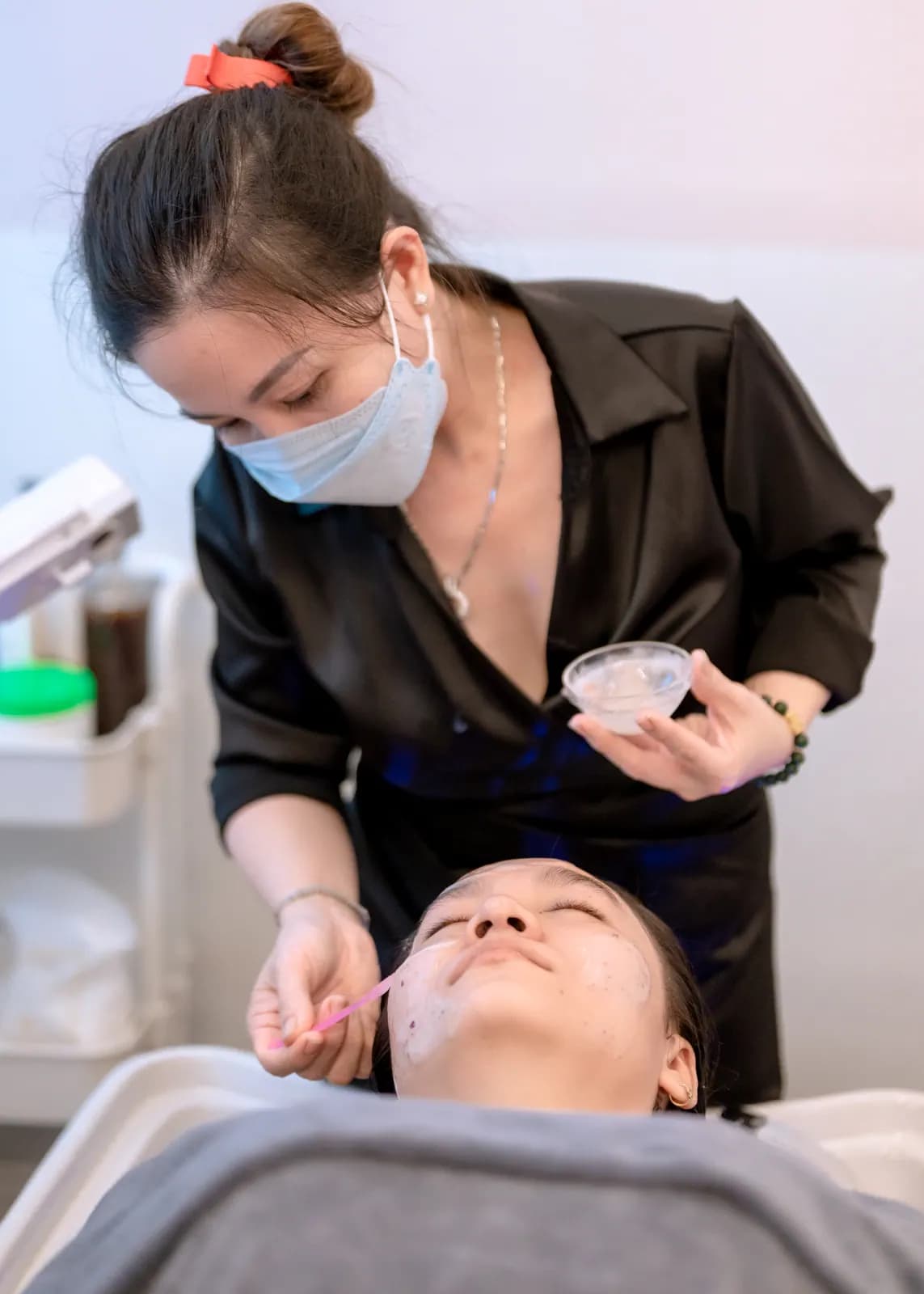 Người đeo khẩu trang cầm chén nhỏ bên người nằm