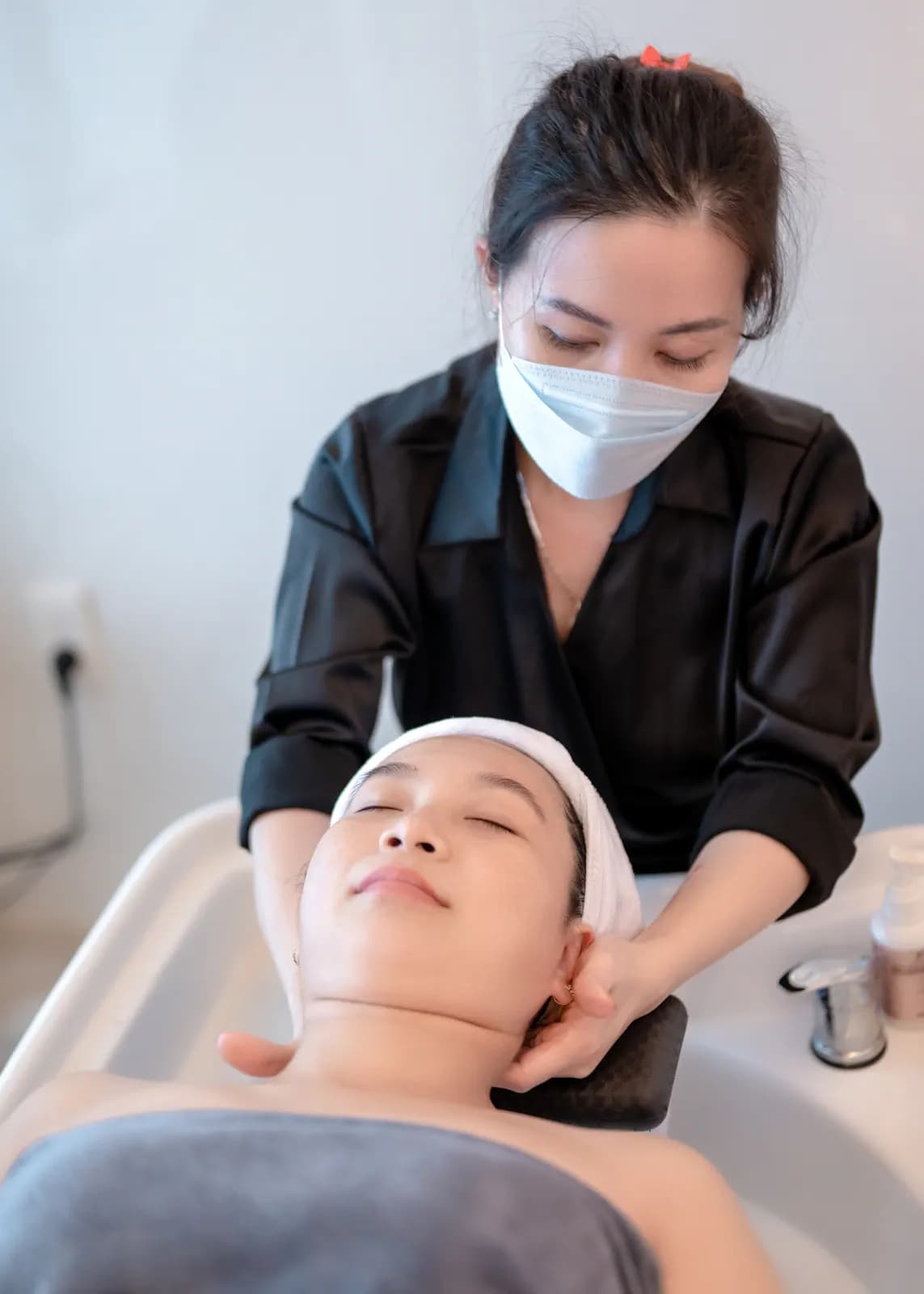 Người đeo khẩu trang đứng bên giường phủ khăn xám
