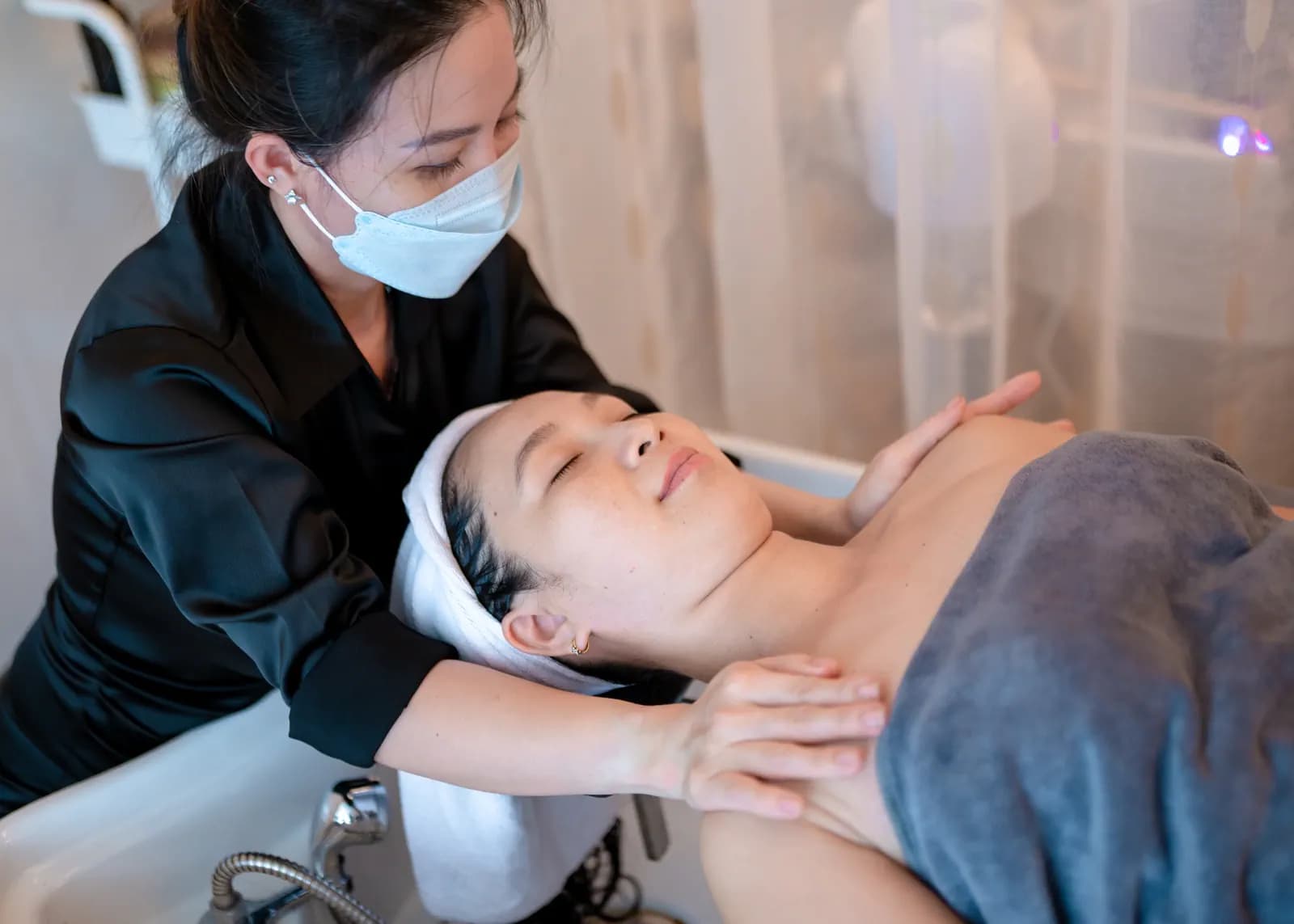 Hai bàn tay đặt bên cổ người nằm cạnh bồn gội