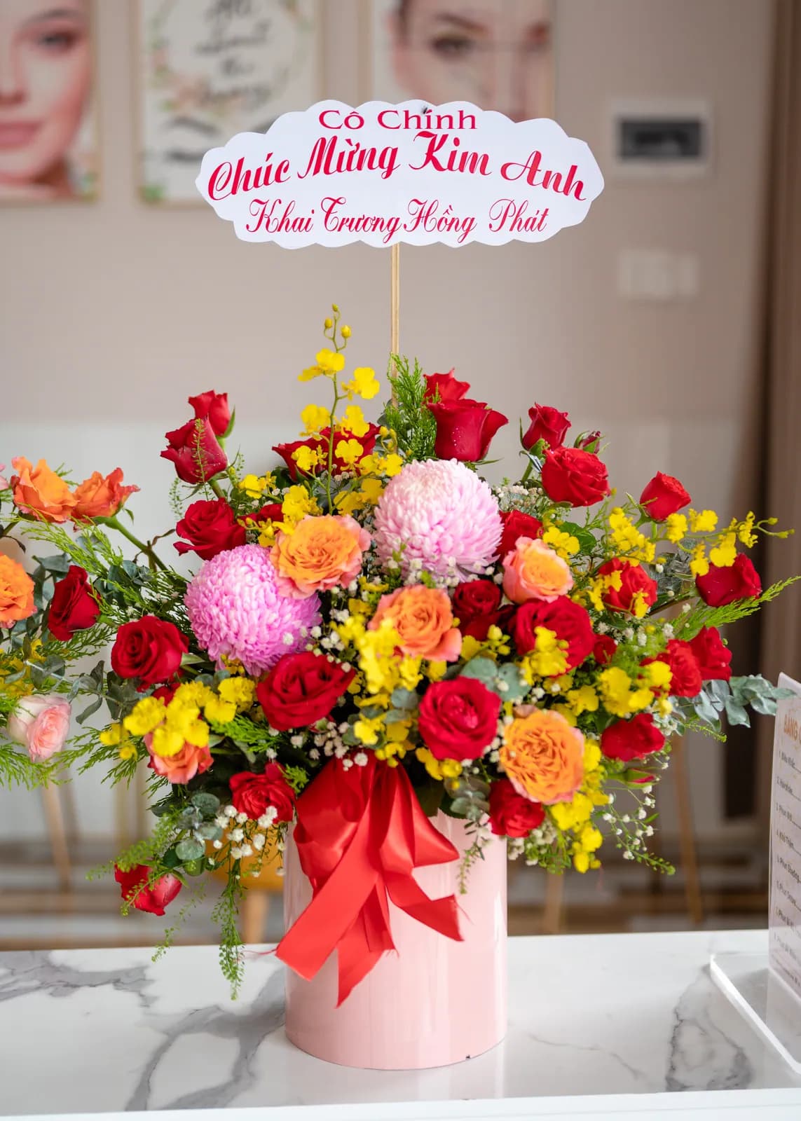 Bó hoa đỏ, vàng và hồng đặt trên bệ trắng