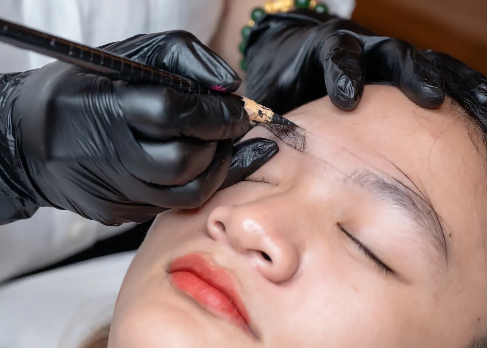 Cận cảnh găng tay đen thao tác ở vùng lông mày