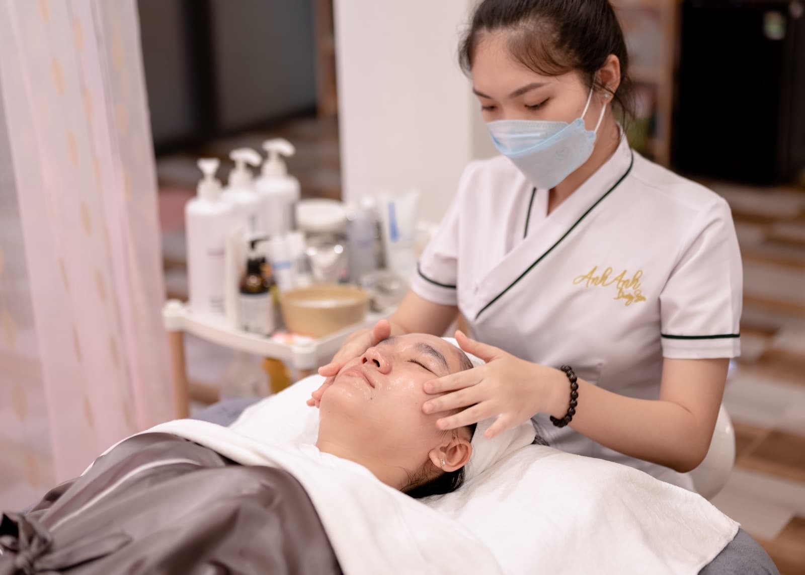 Một người đeo khẩu trang chăm sóc da mặt cho khách trong bộ ảnh Anh Anh