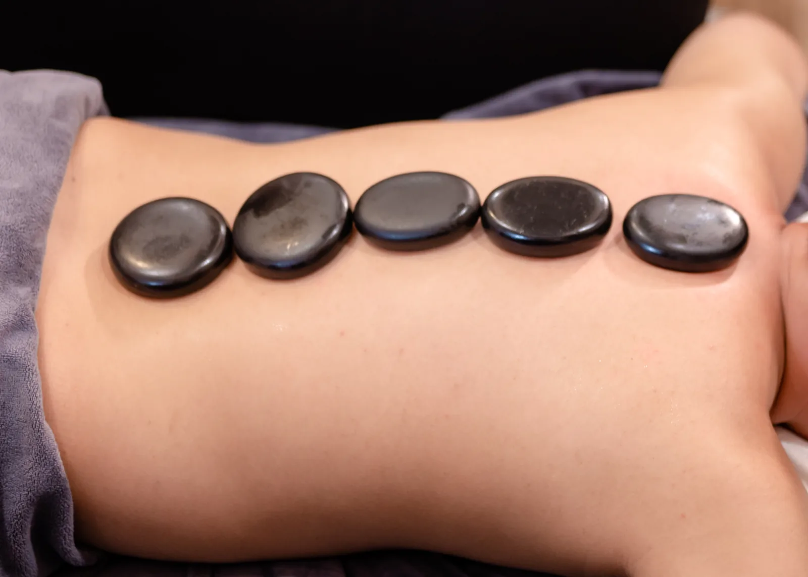 Dark stones placed on a person’s back
