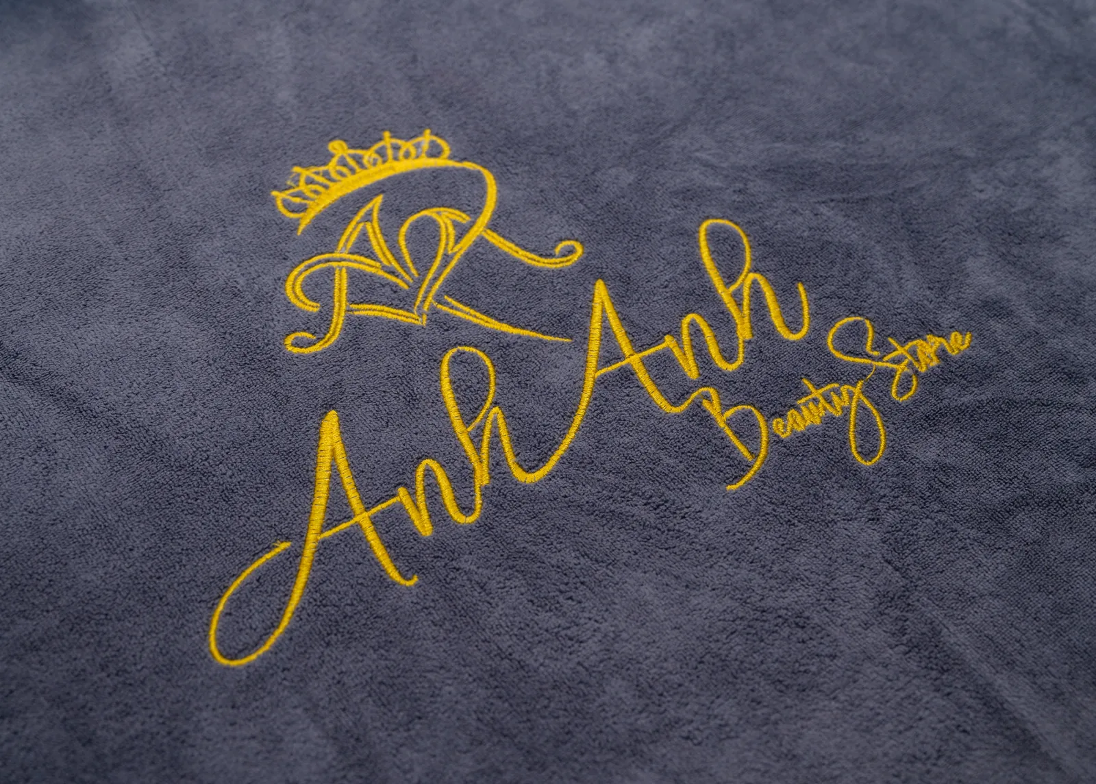The Anh Anh emblem embroidered on charcoal-colored fabric